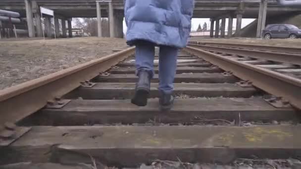 Eine Wanderin läuft im Hintergrund auf einem Bahngleis in einem Industriegebiet am Stadtrand. Mädchen läuft verängstigt vor ihrem Verfolger davon. Konzept von Verbrechen und Gewalt 4k — Stockvideo