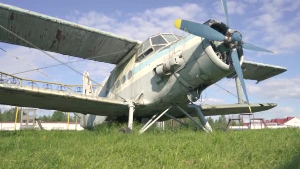 Detailní záběr na trup kokpitu starého letadla SSSR, které stojí v husté trávě zarostlého pole proti západu slunce ve zpomaleném pohybu. Sovětské opuštěné letadlo pro létání na letišti. Opuštěné letadlo 4k — Stock video