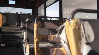 Eski, paslı, deri koltukları hasarlı, terk edilmiş bir otobüsün kırık kabini. Mezarlık geri dönüşüm ve toplu taşıma araçlarının kullanımı. Geri dönüşümlü malzemeler. Çevre koruma kavramı 4k