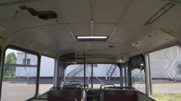 Eski, paslı, deri koltukları hasarlı, terk edilmiş bir otobüsün kırık kabini. Mezarlık geri dönüşüm ve toplu taşıma araçlarının kullanımı. Geri dönüşümlü malzemeler. Çevre koruma kavramı 4k — Stok video