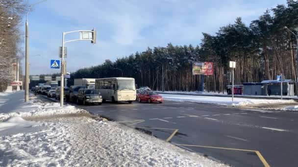 Stadens vägtrafikstockning rör sig i vintersnöstorm. Fotgängare har passerat vägen vid ett trafikljus en vinterdag. Vägtrafik med svåra väderförhållanden. 04.16.2020 Minsk Vitryssland 4k — Stockvideo