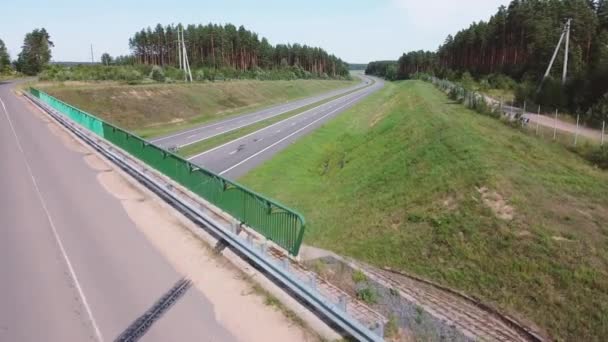 Car drivers with a cargo is driving on an intercity speed highway to customer through a picturesque rural area. Delivery and logistics of goods. Coniferous trees and Hills in Background on a sunny day — 图库视频影像