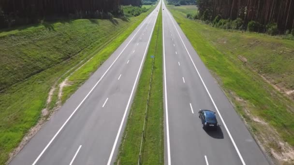 Car drivers with a cargo is driving on an intercity speed highway to customer through a picturesque rural area. Delivery and logistics of goods. Coniferous trees and Hills in Background on a sunny day — Stockvideo