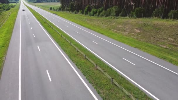 Car drivers with a cargo is driving on an intercity speed highway to customer through a picturesque rural area. Delivery and logistics of goods. Coniferous trees and Hills in Background on a sunny day — стоковое видео