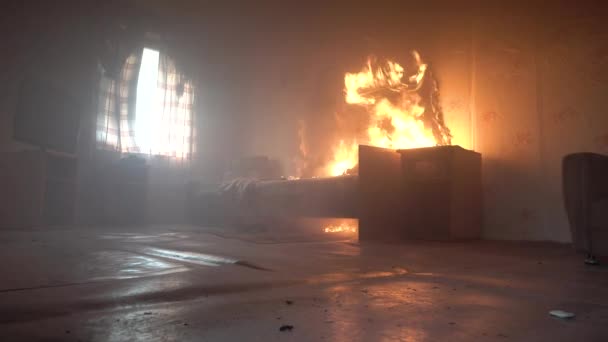 El dormitorio está en llamas con mucho humo. La cama, la mesita de noche, la tetera de plástico, el papel pintado y las estanterías están en llamas en una casa residencial. Fotografía cinematográfica de las secuelas de un incendio de dos alarmas 4k — Vídeo de stock