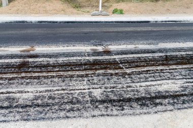 Sokakta taze asfalt tabakası.