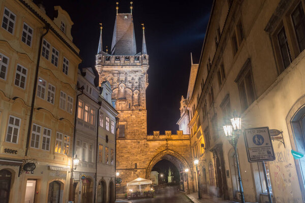 Prague, Czech Republic - July 9, 2020: Malostranska tower and old buildings on Mostecka street at night.