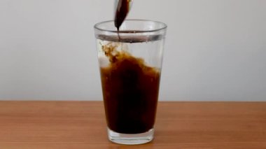 Adding cola concentrate to carbonated mineral water. Making cola from concentrate in a glass.