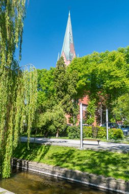 Szczecinek, Poland - May 31, 2021: View in castle park with tower of Church of the Nativity of the Blessed Virgin Mary.