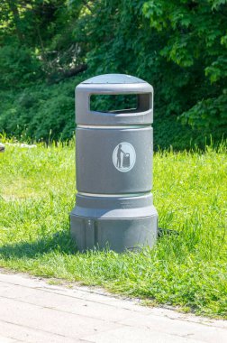 Asfaltın yanındaki yeşil çöp tenekesi. Sokak çöp kutusu.