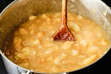 Ahşap kaşıkla pişirme kabında ev yapımı elma reçeli hazırlıyorum. 