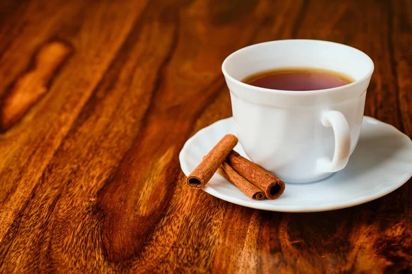 コピースペース付き木製テーブルの上にシナモンとティーカップでおいしいお茶 — ストック写真
