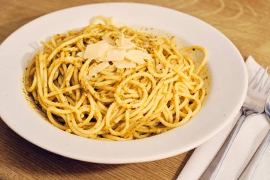 Fesleğen soslu spagetti ve beyaz tabakta peynir.