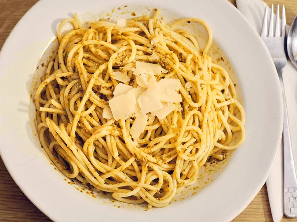 Fesleğen soslu lezzetli spagetti ve beyaz tabakta peynir.