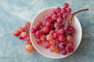 Tasty fresh grape fruit ripe in bowl on blue background