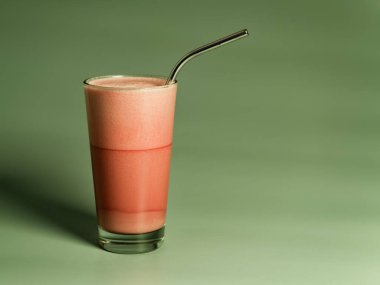 Yeşil arka planda metal pipetli bardakta frappe kahve.