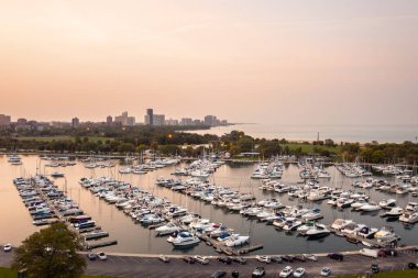 Chicago, IL - 23 Eylül 2020: Montrose limanı, güzel bir sonbahar gününde Michigan Gölü 'nün sakin mavi sularında yelken açarken gün batımında botlarla doluyor..