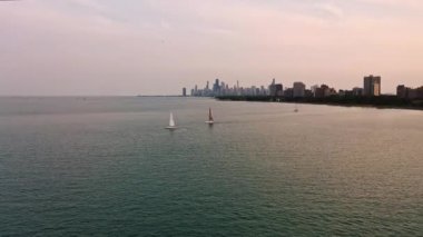 Chicago Skyline 'ın önündeki Michigan Gölü' nün kıyısından geçen birkaç yelkenlinin ve bulutlu bir günde ufukta yükselen binaların hava görüntülerini izlemek çok güzel..