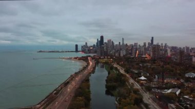 Şikago 'nun hava manzarası Lincoln Park' taki South Lagoon 'da trafik ve şehir ışıkları bulutlu bir akşamda gün batımından hemen önce açılmaya başlarken güzel görünüyor.