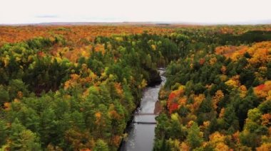 Bad River üzerinde uçan güzel bir hava ve renkli sonbahar yapraklarıyla Copper Falls 'ta bir yaya köprüsü nehir kıyılarını kaplıyor ve Wisconsin Mellen' de sonbaharda ufukta bulutlu bir gökyüzü var..