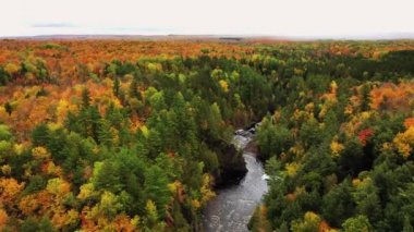Bad River 'ın üzerinde uçan güzel bir hava ve renkli sonbahar yapraklarıyla Copper Falls' da ortaya çıkan kırmızı bir kaya. Nehir kıyılarını kaplıyor ve Wisconsin Mellen 'de sonbaharda ufukta bulutlu bir gökyüzü var..
