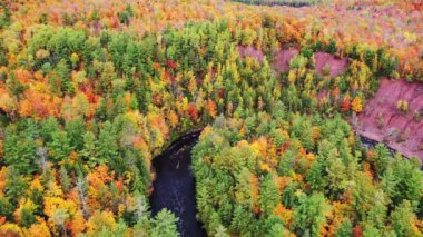 Copper Falls Parkı 'nda sonbaharda Mellen, Wisconsin' de nehir kıyısında yeşil, kırmızı, sarı ve turuncu yapraklarla güzel bir hava dalgası uçuyor..