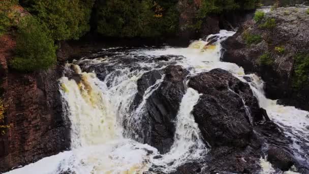 Zblízka vzdušný vznášedlo s výhledem na Horní Potato River Falls vodopád nebo kaskáda, jak těžký proud vody padá dolů z červených a hnědých vytesaných skalnatých útesů na koryto řeky. — Stock video