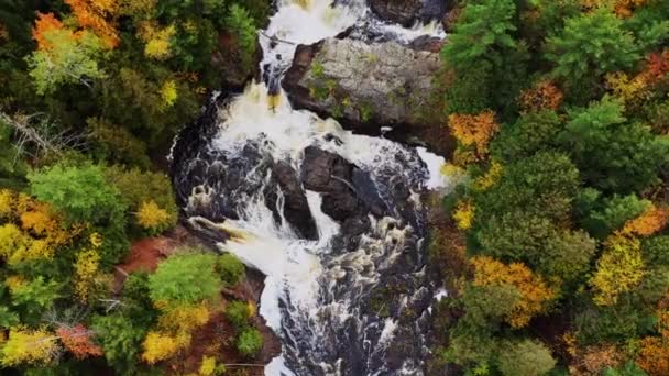 Schöner Herbstblick nach unten über die Oberen Kartoffelfälle mit starkem Wasserfluss, der über die großen Felsformationen mit gelben, orangefarbenen und grünen Bäumen am Flussufer kaskadiert.. — Stockvideo