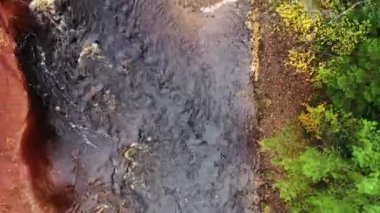 Havadan uçarken kayalık nehir yatağına ve şelalenin hemen aşağısındaki beyaz su akıntısına bakıyorum. Kırmızı toprak kayalık kayalıklar ve nehir kıyılarında ağaçlar var..