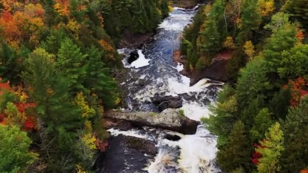 Eine schöne Luftaufnahme, die die Potato River Falls hinunterfliegt, über die oberen Kaskaden, Felsen und Wasserfälle mit grünen, gelben und orangefarbenen Baumblättern oder Herbstlaub, das die Ufer des Flusses im Herbst säumt. — Stockvideo