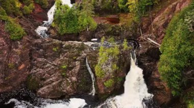 Montreal Nehri 'ndeki Sakson Şelalesi' nin çağlayan ve kayalık uçurumlarında yükselen güzel hava manzarası. Kayalarda ve nehir kıyısında yemyeşil alanlar büyüyor..