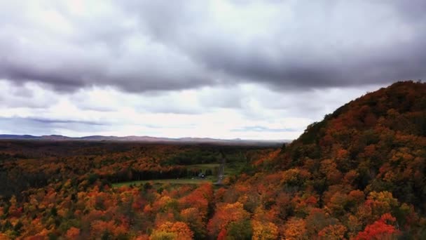 Ongelooflijke herfst opstaan en panning luchtfoto van Copper Peak ski jump heuvel steken hoog in bewolkte en bewolkte lucht boven omgeven door kleurrijke rode, oranje, gele en groene boom gebladerte — Stockvideo