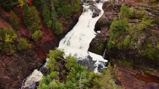 Schöne Luftaufnahme, die die Kaskaden und felsigen Klippen des Saxon Falls Wasserfalls am Montreal River hinauffliegt, mit immergrünen Pflanzen, die an Felsen und Flussufern wachsen. — Stockvideo