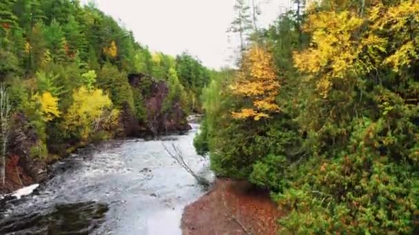Schöne Luftaufnahme über einer Felsformation im Bad River bei den Copper Falls mit farbenfrohem, grünem, rotem, gelbem und orangefarbenem Herbstlaub, während es in Mellen, Wisconsin im Herbst zu regnen beginnt. — Stockvideo