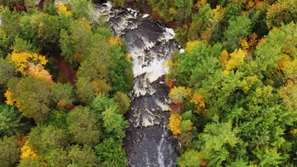 Hermoso vuelo aéreo sobre las cascadas y Brownstone Falls en el río Tyler Forks, ya que se fusiona con Bad River con colorido follaje de otoño que bordea las orillas del río en otoño en Copper Falls park. — Vídeos de Stock