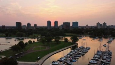 Chicago, IL - 23 Eylül 2020: Yelkenlilerin Michigan Gölü boyunca süzülüp Montrose limanına yanaşmasıyla güneş gökyüzünü pembeye ve turuncuya döndürmeye başlıyor.