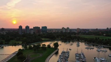 Chicago, IL - 23 Eylül 2020: Yelkenliler Montrose limanına dönerken güneş gökyüzünü pembeye ve turuncuya döndürmeye başlıyor.