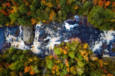 Yukarı Patates Nehri Şelaleleri 'nin çağlayan şelaleleri ve beyaz su akıntılarının Wisconsin' deki yaprak döken ve yemyeşil orman çöllerini keserken çekilmiş güzel bir fotoğrafı..