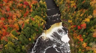 Havadan aşağıya güzel bir bakış geliyor Tahquamenon şelalesinden şelaleye doğru çekiliyor ve aşağıdaki turist izleme platformu yemyeşil ağaçlar ve sonbahar yaprakları ile çevrili..