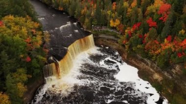 Havadan yükselen ve Tahquamenon Şelalesi 'nin üzerinde dönen hava turistlerin nehre dökülüşünü izlediği gibi kayalıklar yemyeşil ağaçlar ve sonbahar yapraklarıyla kaplı..