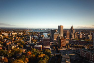 Providence, RI - 21 Ekim 2020: Yüksek binalar, bacalar, rüzgar türbinleri ve kilise kulesi şehir merkezindeki Moshassuck ve Providence nehirlerine bakarak şehrin ufuk çizgisini belirler..