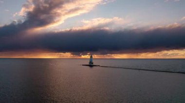 Beyaz renkli Ludington dalgalı deniz fenerinin önünde gün batımının güzel görüntüsü. Mavi ve turuncu gökyüzü ve Michigan Gölü 'nün suyuna yansıyan bulutlar..