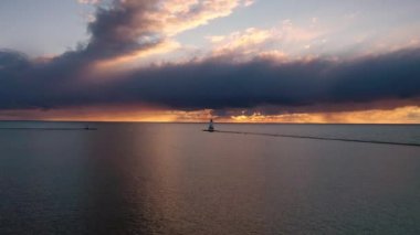 Beyaz renkli Ludington dalgalı deniz fenerinin günbatımı antenini mavi ve turuncu gökyüzü ve yukarıda Michigan Gölü 'nün suyuna yansıyan bulutlarla çekmek çok güzel..