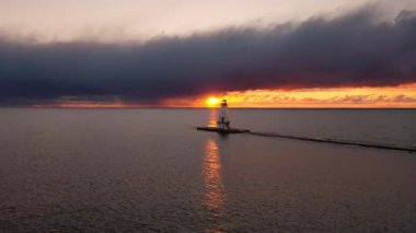 Ludington Dalgakıran Deniz Feneri 'nin parlak turuncu ve sarı güneşli güzel antenleri. Yapının arkasında parlıyor. Suyu yansıtıyor ve gün batımında gökyüzündeki bulutları aydınlatıyor..