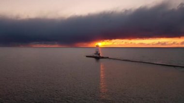 Ludington Dalgakıran Deniz Feneri 'nin parlak turuncu ve sarı güneşli güzel antenleri. Yapının arkasında parlıyor. Suyu yansıtıyor ve gün batımında gökyüzündeki bulutları aydınlatıyor..