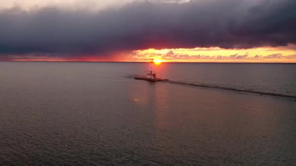 ミシガン湖の水を反映し カラフルなピンク オレンジと黄色の色で空と雲を照らす太陽とルディントン防波堤灯台の美しいパノラマ — ストック動画