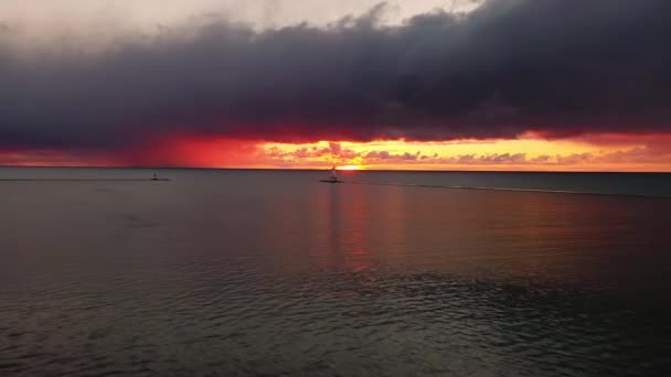 ミシガン湖の水を反射し カラフルなピンク オレンジ 黄色で空と雲を照らす太陽とルディントン防波堤灯台の空中で美しいパンニング — ストック動画