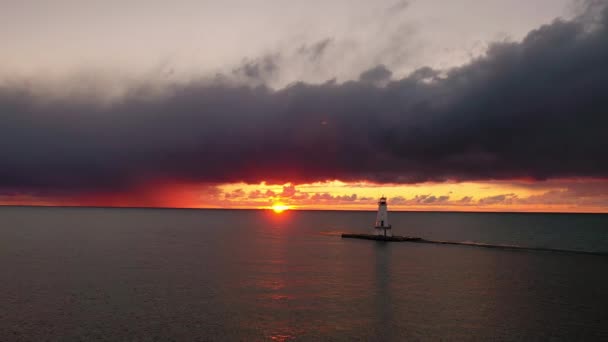 ミシガン湖の水を反映し カラフルなピンク オレンジと黄色の色で空と雲を照らす太陽とルディントン防波堤灯台の美しいパノラマ — ストック動画