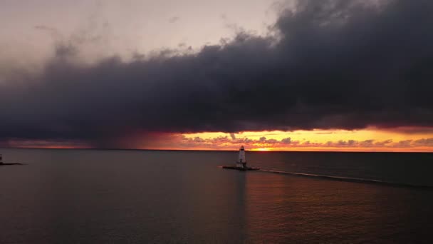 ピンクとオレンジの空と雲の上に白い色のラディントン防波堤灯台の美しいパニング日没の航空機は ミシガン湖の穏やかなまたは静かな水を反映しています — ストック動画