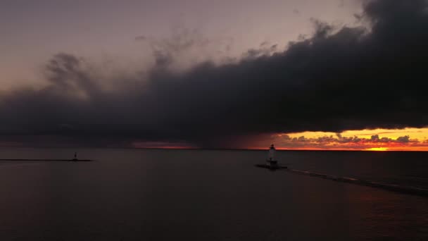 光が点滅し ピンクとオレンジの空とミシガン湖の水に反映雲と白い色のラディントン防波堤灯台の美しいパニング日没の航空機 — ストック動画